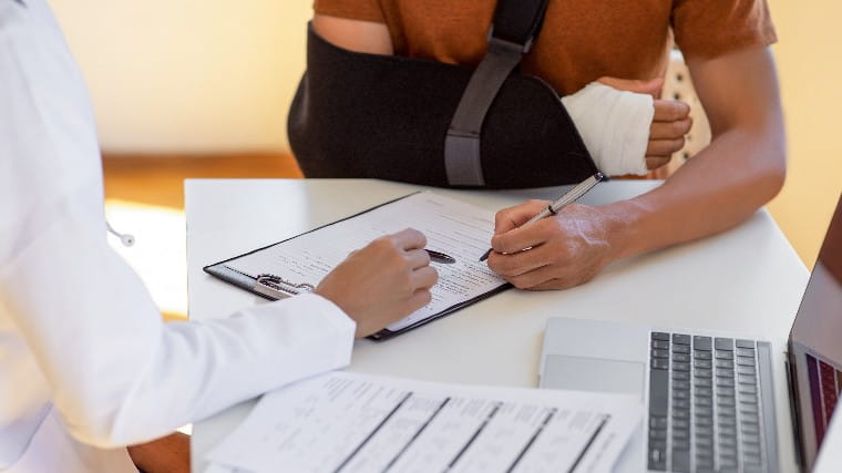 Man with broken arm signing medical forms.