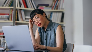 Stressed woman reading information on laptop.