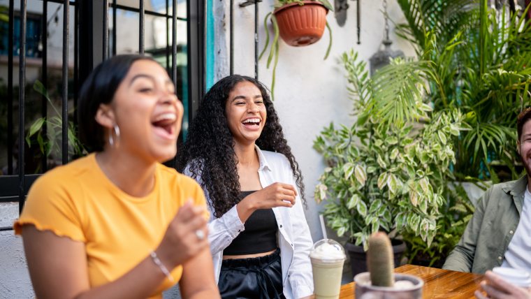 Gen Z customers smiling and sitting outside restaurant.